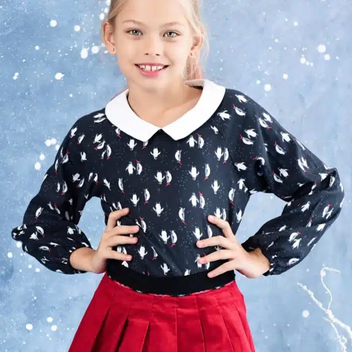 Blouse spéciale fêtes de Noël noir avec imprimé pingouin blanc et rouge, col Claudine blanc, manches élastiques aux poignets. Mode fille de la marque Française en commerce équitable LA FAUTE A VOLTAIRE
