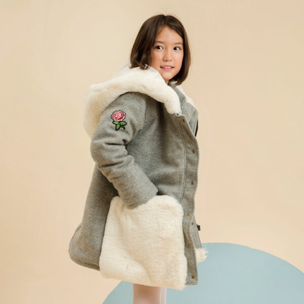 Oversize coat in mouse gray wool, giant pockets and hoods in off-white faux fur, pink flower crest, adjustable handle with faux fur on the wrists. French fair trade fashion brand LA FAUTE A VOLTAIRE