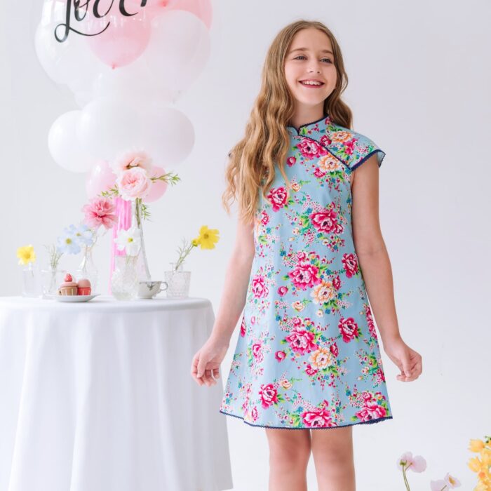 Offrez cette Magnifique Robe Chinoise à Col Mao et Manches Courtes Coupées en biais en Coton Bleu Turquoise Fleuri Rose Fuchsia pour Filles, Fillettes et Ados de 2 à 16 ans. Délicate Dentelle Bleu Marine sur les emmanchures, l'encolure et le bas de la Robe. Modèle Annam de la Marque de Mode Française pour Enfants produite en Commerce Équitable La Faute à Voltaire.