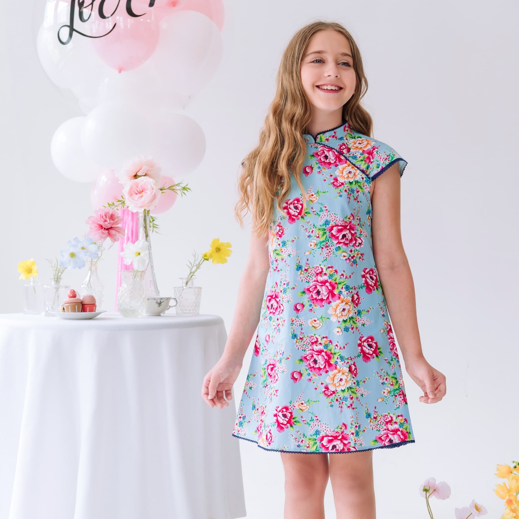 Offrez cette Magnifique Robe Chinoise à Col Mao et Manches Courtes Coupées en biais en Coton Bleu Turquoise Fleuri Rose Fuchsia pour Filles, Fillettes et Ados de 2 à 16 ans. Délicate Dentelle Bleu Marine sur les emmanchures, l'encolure et le bas de la Robe. Modèle Annam de la Marque de Mode Française pour Enfants produite en Commerce Équitable La Faute à Voltaire.
