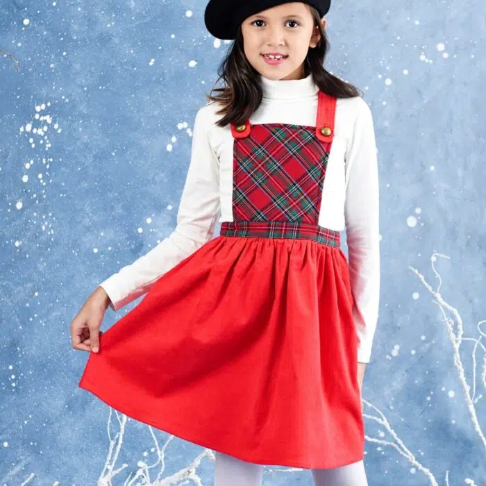 Une Adorable Robe de Noël pour Fille façon Salopette avec Bretelles Ajustables. Très Originale en Velours Rouge en Bas et Plastron Avant en Carreaux Tartan Rouge et Vert. Très Confortable avec Taille Élastique. Modèle Spécial Fêtes de Noël pour Enfant de la Marque de Mode pour Enfant La Faute à Voltaire.