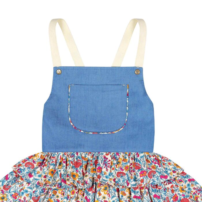 Girl's summer dungaree dress with blue denim cotton top and blue floral ruffle bottom, pink, with adjustable cross back straps. Ruffled overalls dress for girls of the children's fashion brand LA FAUTE A VOLTAIRE