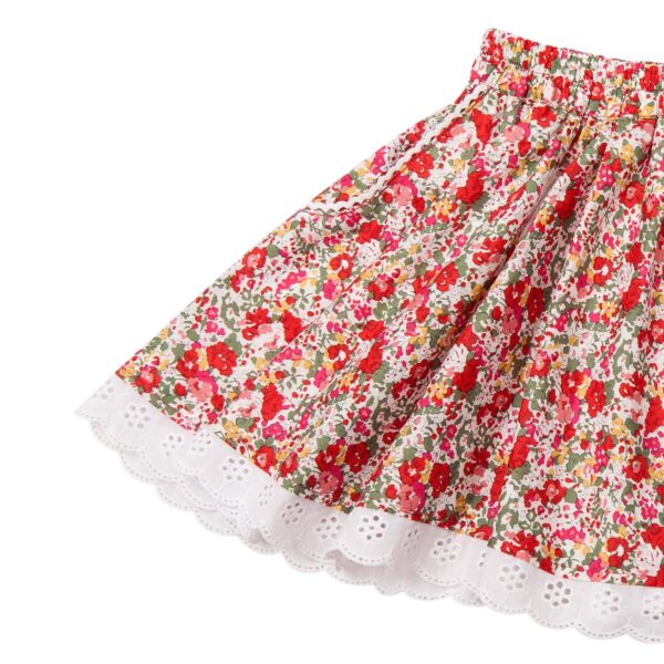 Pretty skirt that turns for girls in red liberty cotton and white lace with pockets and white English embroidery at the bottom of the skirt. Extendable elastic belt. Length above the knee. Skirt of the children's fashion brand LA FAUTE A VOLTAIRE