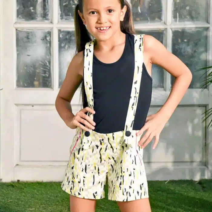 short salopette coton imprimé blanc, gris, jaune avec biais rose fuchsia et gros bouton décoratif noir. Dos amovible avec boutons intérieur. Shorts salopette pour filles et. fillettes de la marque de mode pour enfants LA FAUTE A VOLTAIRE