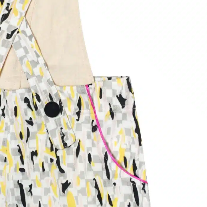 short salopette coton imprimé blanc, gris, jaune avec biais rose fuchsia et gros bouton décoratif noir. Dos amovible avec boutons intérieur. Shorts salopette pour filles et. fillettes de la marque de mode pour enfants LA FAUTE A VOLTAIRE