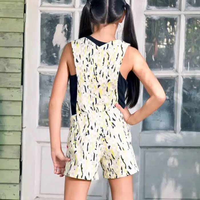 short salopette coton imprimé blanc, gris, jaune avec biais rose fuchsia et gros bouton décoratif noir. Dos amovible avec boutons intérieur. Shorts salopette pour filles et. fillettes de la marque de mode pour enfants LA FAUTE A VOLTAIRE