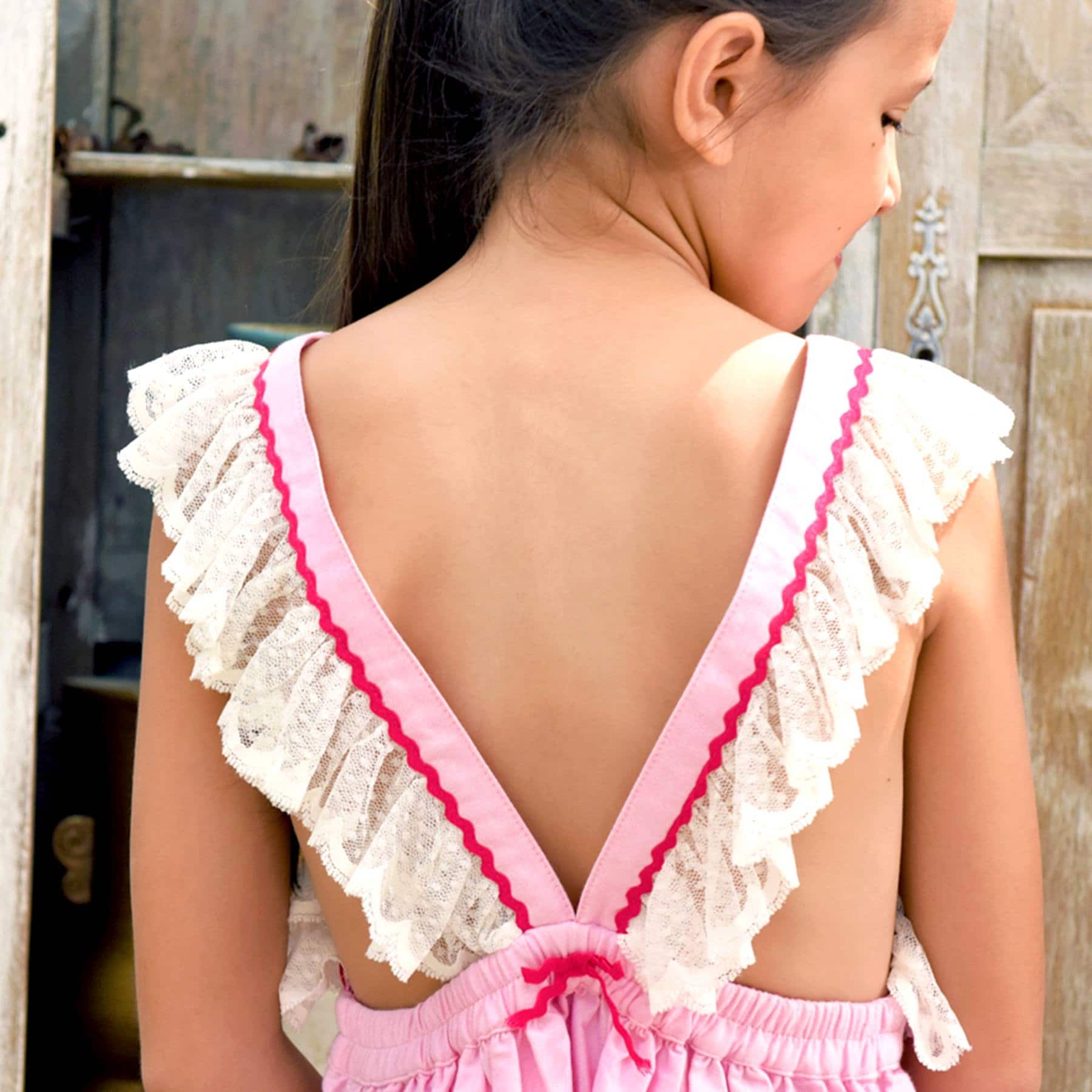 Pale pink bohemian dress with fine beige lace straps, bare back, elastic waist, fuchsia pink detailing from the brand of. fashion for children LA FAUTE A VOLTAIRE