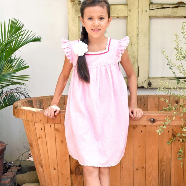 Loose pink summer girl dress with white polka dots, short sleeves with ruffles trimmed with lace from the fair trade children's fashion brand LA FAUTE A VOLTAIRE