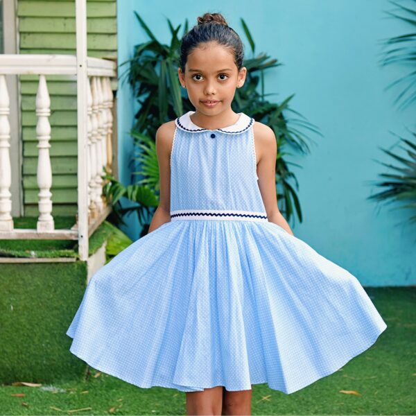 Adorable girls' formal dress that turns horizontally in light blue cotton with white polka dots, Claudine collar and fitted white belt with navy blue zigzag band. Procession dress of the fashion brand for children and teenagers LA FAUTE A VOLTAIRE