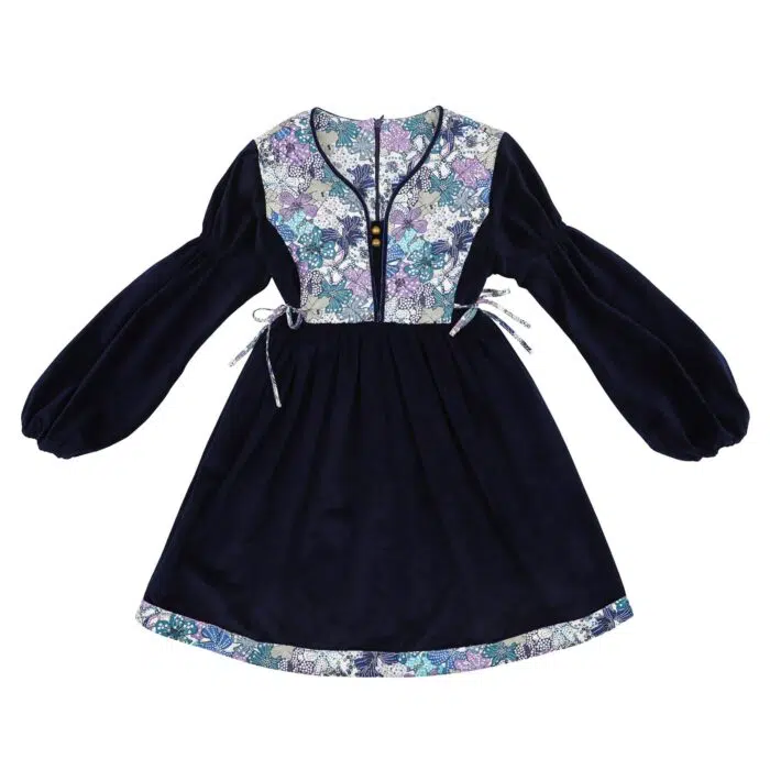 On Craque pour cette Élégante et Originale Robe d'Hiver pour Fille en Velours Millerais Bleu Marine et plastron matelassé en Fleuri Liberty Violet et Lilas de la Marque de Mode pour Enfant La Faute à Voltaire.