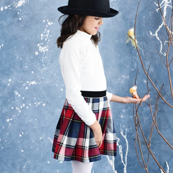 Tartan wool skirt in navy blue and red plaid for girls and teens from 2 to 16 years old, with integrated black velvet belt and contrasting gold bias. Side closure with snap and zipper. French designer brand of LA FAUTE A VOLTAIRE