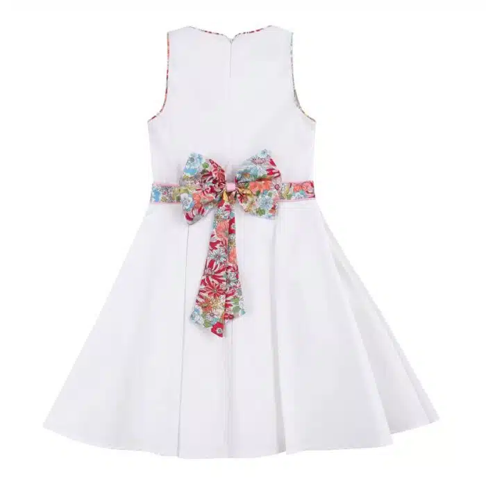 Robe de cortège blanche pour filles et fillettes avec ceinture en tissu fleuri liberty rose, noeud dans le noeud, sans manche avec emmanchures américaine. Modèle hepburn de la marque de mode pour enfant LA FAUTE A VOLTAIRE