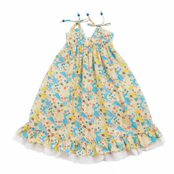 Jolie robe qui tourne en coton avec des imprimés fleuris jaune et bleu, avec des fines bretelles, de la dentelle blanche et des volants. Robe de la marque de mode pour enfants et ados LA FAUTE A VOLTAIRE.