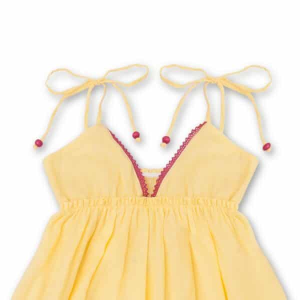 Jolie robe qui tourne en coton jaune, avec des fines bretelles, de la dentelle rose et des volants. Robe de la marque de mode pour enfants et ados LA FAUTE A VOLTAIRE.