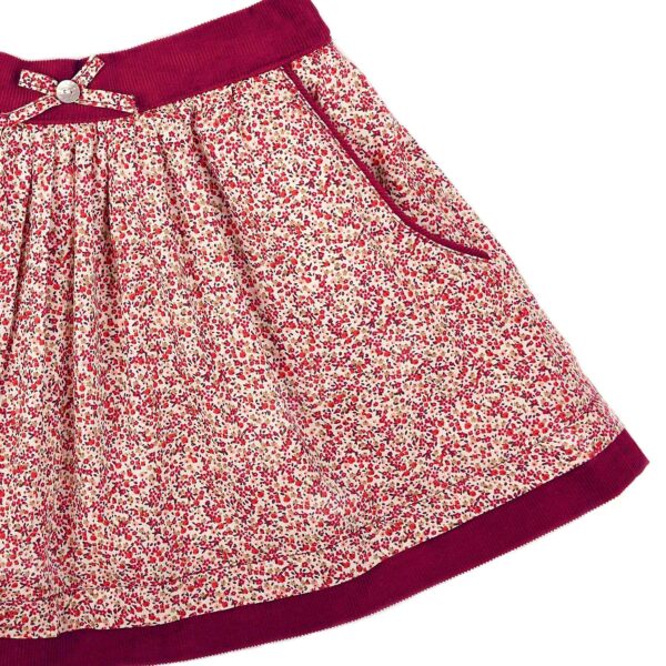Pretty skirt for girls in red flowery liberty cotton, bordered with burgundy velvet pockets and elasticated velvet belt. Skirt model LILOU of the fashion brand for children and teenagers LA FAUTE A VOLTAIRE.