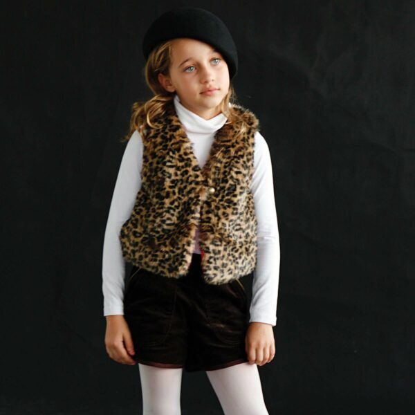 Cute shepherd's vest without sleeves for girl with leopard print, in very soft fake fur, and a closure with a nice round button bronze color. Cotton lined vest. Model PETITE BERGERE of the fashion brand for children and teenagers LA FAUTE A VOLTAIRE.