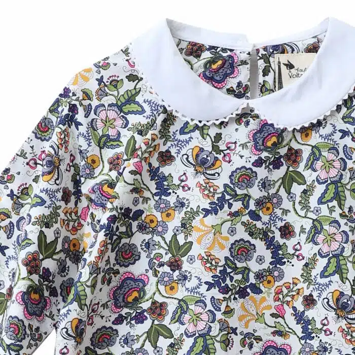 Jolie blouse pour filles et ados de 2 à 16 ans en coton fleuri liberty rose et multicolore, à col Claudine blanc bordé de fine dentelle anglaise blanche, à manches longues ajustables et élastiques aux poignets. Modèle Claudine de la marque de mode pour enfant LA FAUTE A VOLTAIRE
