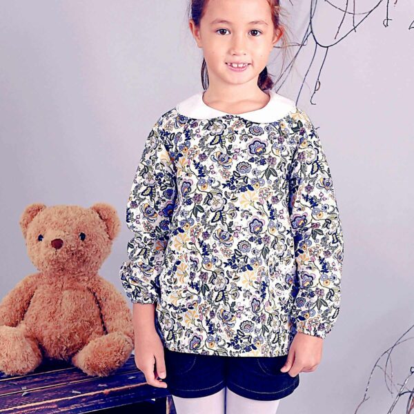 Pretty blouse for girls and teenagers from 2 to 16 years old in pink and multicolored flowery cotton, with white Claudine collar edged with fine white English lace, with adjustable long sleeves and elastic cuffs. Claudine model of the fashion brand for children LA FAUTE A VOLTAIRE