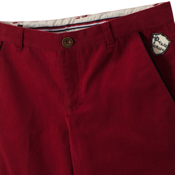 Un Très Beau Pantalon Coupe Chino en Coton Rouge Bordeaux de la Marque de Mode Française Chic pour Enfant La Faute à Voltaire. Vous aimerez les Détails comme le Biais de Coton Noir sur les Poches Raglan, l'Écusson La Faute à Voltaire à l'Angle d'une Poche, le Confort de cette Coupe Ample aux Cuisses pour les Garçons et Ados de 2 à 16 ans, Resserré aux Chevilles, l'Élastique Intérieur qui permet d'Adapter la Largeur de la Taille. Ruban Décoratif Bleu, Blanc, Rouge à l'intérieur de la ceinture ainsi que de chaque côté de l'intérieur du bas du pantalon pour pouvoir le rouler vers l'extérieur si le pantalon est trop Long avec une petite Fantaisie.