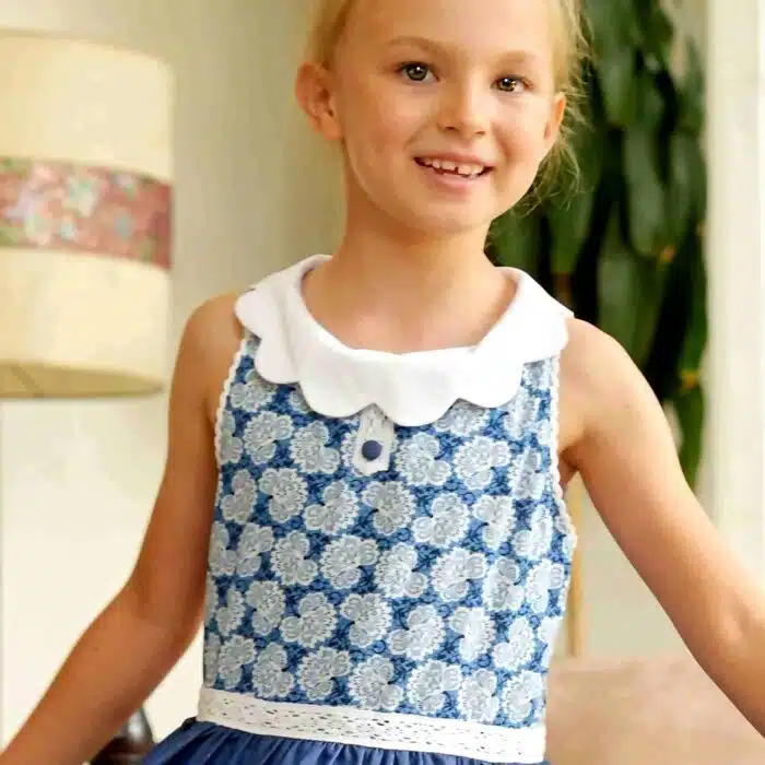 Magnifique robe qui tourne en fin coton denim en bas et beau coton fleuri bleu roi et blanc en haut, avec col blanc forme pétale, ceinture en dentelle blanche, sans manche. Modèle HEPBURN pour filles et ados de 2 à 16 ans de la marque de mode LA FAUTE A VOLTAIRE