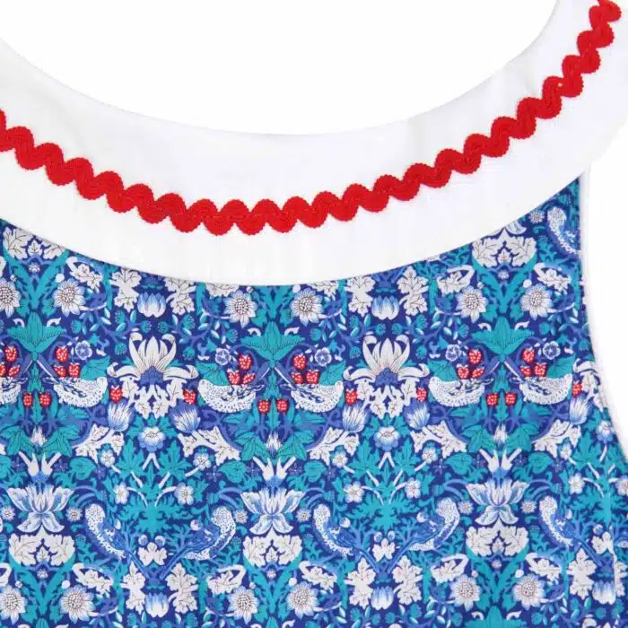 Pour un mariage rétro-chic, une fête estivale, on craque pour cette élégante robe d'été qui tourne à l'horizontal à l'imprimé floral et oiseaux bleu marine, vert et rouge, large col bateau blanc avec dentelle en zigzag rouge, ceinture blanche, emmanchure américaine pour filles de 2 à 16 ans de la marque de mode pour enfants LA FAUTE A VOLTAIRE