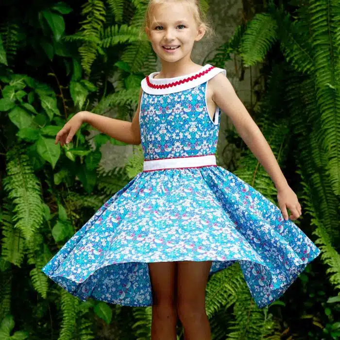 Pour un mariage rétro-chic, une fête estivale, on craque pour cette élégante robe d'été qui tourne à l'horizontal à l'imprimé floral et oiseaux bleu marine, vert et rouge, large col bateau blanc avec dentelle en zigzag rouge, ceinture blanche, emmanchure américaine pour filles de 2 à16 ans de la marque de mode pour enfants LA FAUTE A VOLTAIRE