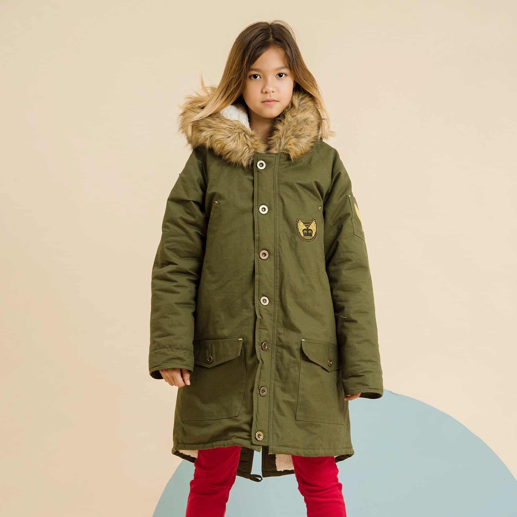 Parka oversize tendance disponible en taille pour enfant, femmes et hommes en toile de coton kaki avec écusson militaire et grosse capuche et doublure en fausse fourrure de la marque de mode pour enfant LA FAUTE A VOLTAIRE.