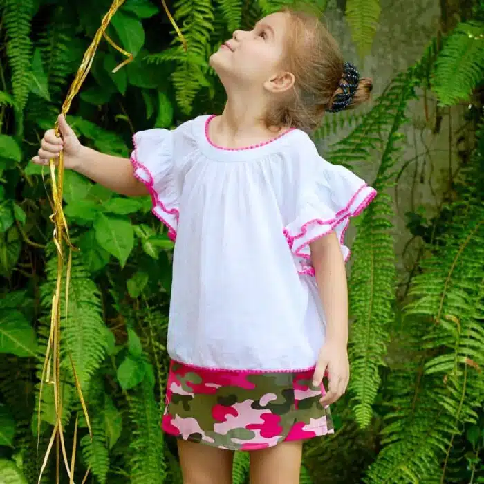 Jolie blouse blanche été fille, coupe ample et confortable, à manches papillon. Originale avec sa double rangée de volants sur les manches bordés de pompons rose fuchsia. Col V dans la nuque, bas de la blouse soulignés de pompons rose fuchsia. Blouse été pour filles, fillettes et ados de 2 à 16 ans, de la marque de mode pour enfants LA FAUTE A VOLTAIRE