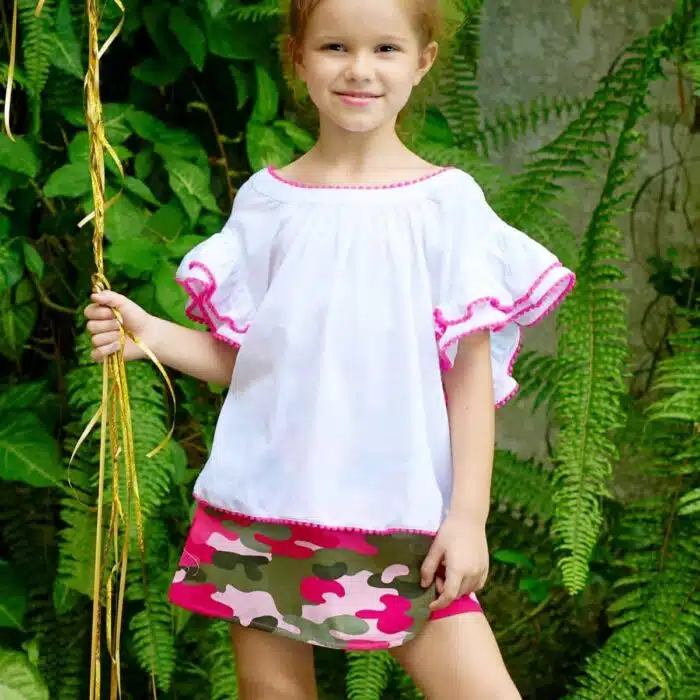 Jolie blouse blanche été fille, coupe ample et confortable, à manches papillon. Originale avec sa double rangée de volants sur les manches bordés de pompons rose fuchsia. Col V dans la nuque, bas de la blouse soulignés de pompons rose fuchsia. Blouse été pour filles, fillettes et ados de 2 à 16 ans, de la marque de mode pour enfants LA FAUTE A VOLTAIRE