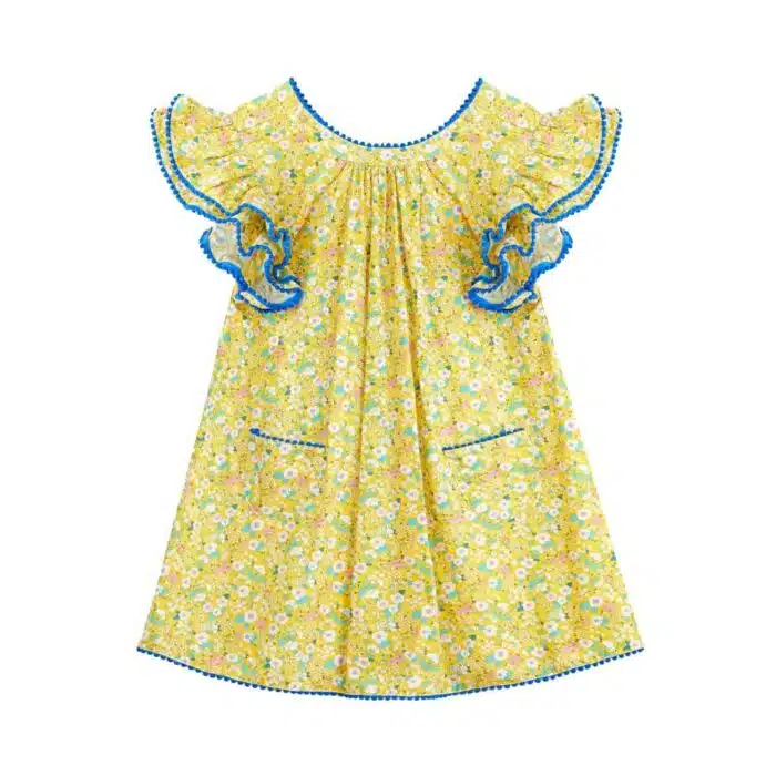 Jolie robe fleurie liberty jaune à petites fleurs rose, bleu turquoise, vert pâle, avec une double rangée de volants aux manches style papillon, col V dans la nuque, pompons bleu roi autour du col, des manches et. bas de la robe. Robe été pour filles, fillettes et ados de la marque de mode La Faute à Voltaire