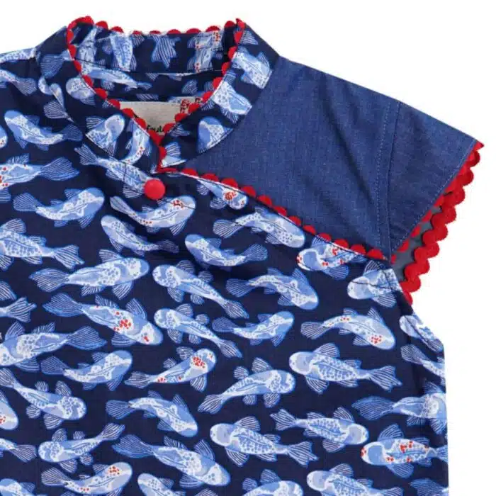 Blouse chinoise en coton imprimé poissons Khoi bleu marine, bleu clair et rouge. Les manches courtes coupées en biais, le col Mao et le bord de la blouse bordée de biais rouge. Blouse asiatique pour filles, fillettes et ados de la marque de mode pour enfants LA FAUTE A VOLTAIRE