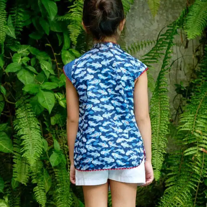 Blouse chinoise en coton imprimé poissons Khoi bleu marine, bleu clair et rouge. Les manches courtes coupées en biais, le col Mao et le bord de la blouse bordée de biais rouge. Blouse asiatique pour filles, fillettes et ados de la marque de mode pour enfants LA FAUTE A VOLTAIRE