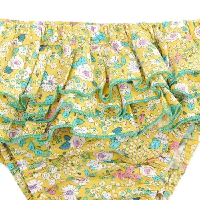 Maillot de bain deux pièces à volants en coton fleuri jaune et vert. Haut du maillot forme bandeau à volant avec élastique dans le dos et bas du maillot coupe taille basse à volants. Maillot de bain deux pièces pour filles, fillettes et ados de la marque de mode pour enfant LA FAUTE A VOLTAIRE