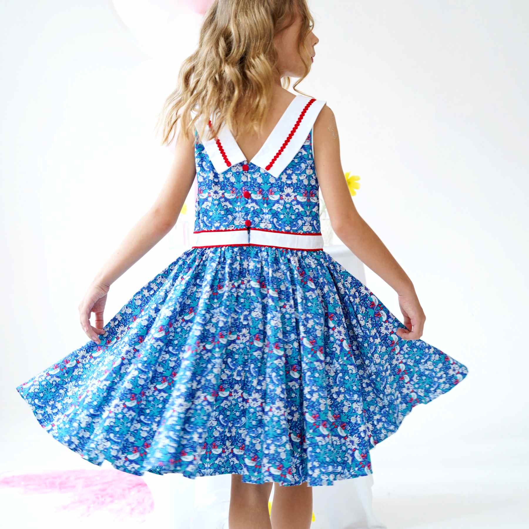 On Craque pour cette Magnifique Robe Qui Tourne Bleu Foncé à l'Imprimé Fleuri Liberty avec Fleurs, Oiseaux blanc et Rouge. Robe d'Été Sans Manche avec Col Bateau Blanc en V dans la Nuque avec Ruban Zigzag Rouge, Taille Cintrée avec Ceinture Intégrée Blanche Bordé de Zigzag Rouge. Deux Poches Invisibles sur les Côtés. Parfaite pour une Cérémonie Religieuse comme un Mariage ou une Fête de Famille, une Garden Party. Robe Qui Tourne pour Filles, Fillettes, Ados de 2 à 16 ans. Livraison Rapide 24-72h Offerte pour Tout achat Supérieur à 60€. Marque de Mode Créateur Française Produite en Commerce Équitable La Faute à Voltaire.