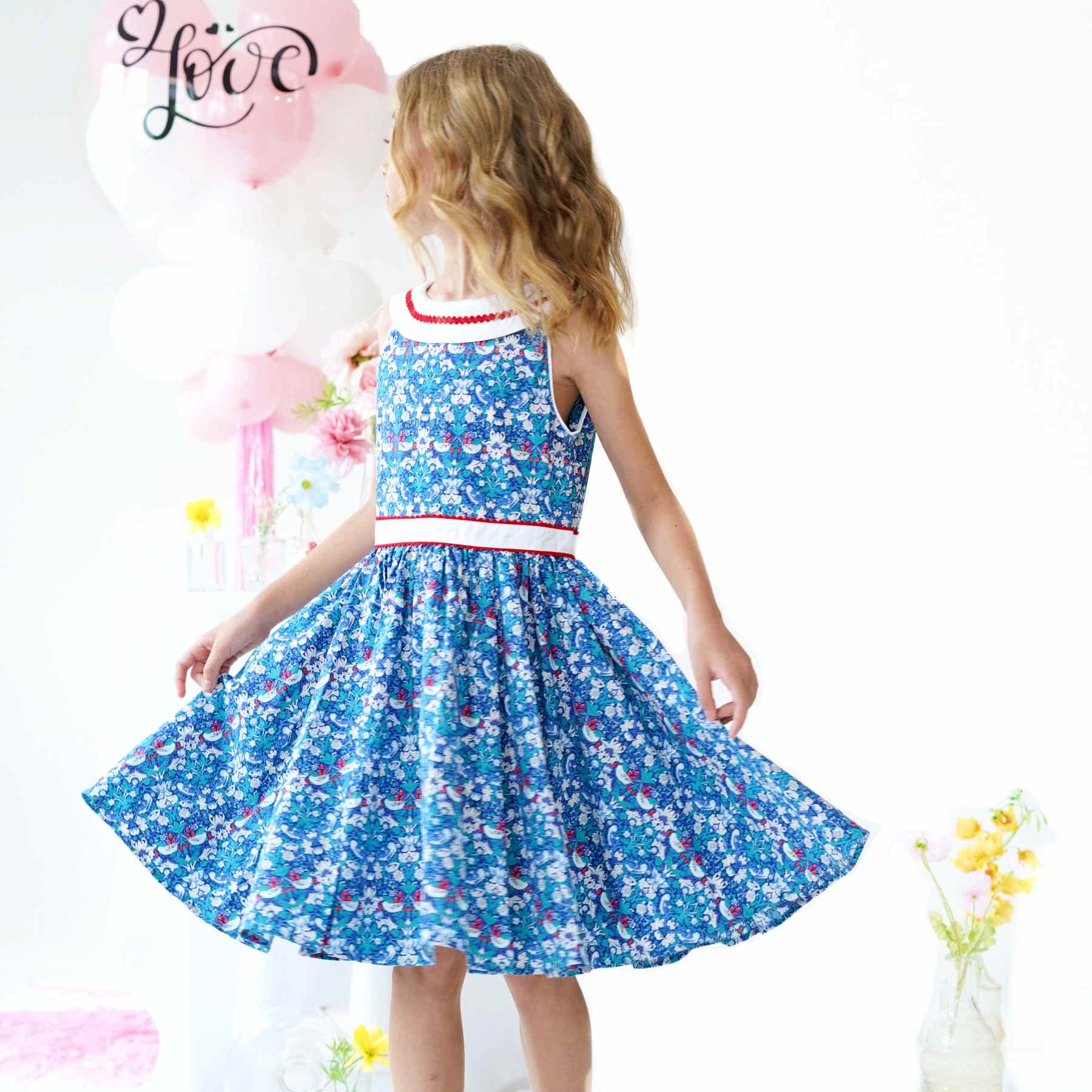 On Craque pour cette Magnifique Robe Qui Tourne Bleu Foncé à l'Imprimé Fleuri Liberty avec Fleurs, Oiseaux blanc et Rouge. Robe d'Été Sans Manche avec Col Bateau Blanc en V dans la Nuque avec Ruban Zigzag Rouge, Taille Cintrée avec Ceinture Intégrée Blanche Bordé de Zigzag Rouge. Deux Poches Invisibles sur les Côtés. Parfaite pour une Cérémonie Religieuse comme un Mariage ou une Fête de Famille, une Garden Party. Robe Qui Tourne pour Filles, Fillettes, Ados de 2 à 16 ans. Livraison Rapide 24-72h Offerte pour Tout achat Supérieur à 60€. Marque de Mode Créateur Française Produite en Commerce Équitable La Faute à Voltaire.