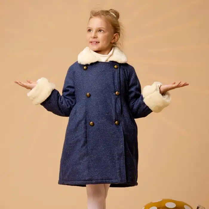 Un Magnifique Manteau Chaud et Long en Laine Tweed Bleu Marine avec Col et Poignets en Fausse Fourrure toute Douce Beige. Cet élégant Manteau est. doublé de Coton fleuri Liberty Jaune et Bleu Ciel. Evolutif, ce Manteau se porte mi-genou ou jusqu'à 10 cm au dessus du genou. Les manches bordées de fausse fourrure se retournent pour s'adapter à la longueur de votre enfant. Ainsi ce manteau évolutif se porte deux années très facilement et est très économique. Manteau de la Marque de Mode Vêtements Chic pour Enfant La Faute à Voltaire.