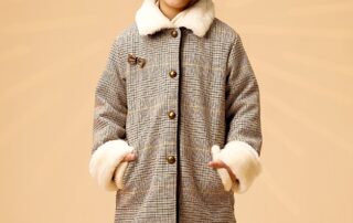 Un Manteau pour Fille très Élégant et Tendance à Carreaux Tartan Marron et Jaune avec un Col et bout des Manches. en Fausse Fourrure Beige Toute Douce. Ce Manteau très Raffiné se Ferme sur l'Avant avec des Gros Boutons Couleur Bronze. Très Original, il dispose d'un Petit Noeud Doré sur La Poitrine, un Biais Velours Marron le Long de la Boutonnière. Sa Doublure en Coton Fleuri Liberty Jaune et Bleu Pâle apporte un Contraste très Mode. Économique, ce Manteau pour Enfant Évolutif possède des Manches qui s'adaptent à la Longueur des Bras de votre Princesse permettant de porter ce Beau Vêtement deux Années de Suite. Manteau Nouvelle Collection Automne Hiver de la Marque de Mode Vêtement Chic pour Enfant La Faute à Voltaire.