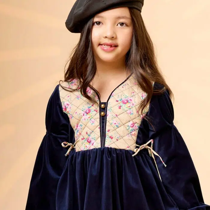 On Craque pour cette Élégante et Originale Robe d'Hiver pour Fille en Velours Millerais Bleu Marine et plastron matelassé en Fleuri Liberty Beige et Rose de la Marque de Mode pour Enfant La Faute à Voltaire.