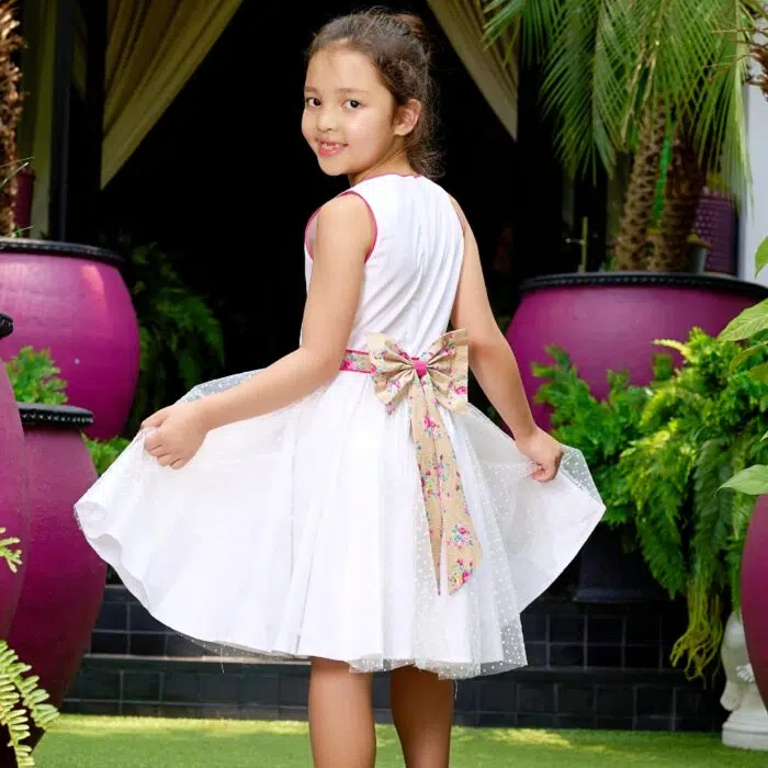 Une Magnifique Robe de Cérémonie Qui Tourne en Coton Blanc Contrasté de Coton Fleuri Liberty Beige et Rose, et de Tulle Blanche sur la Jupe. Un Gros noeud Fleuri Amovible dans le Dos. Robe demoiselle d'honneur pour Fille, Fillette de 2 à 16 ans de la Marque de Mode Enfantine La Faute à Voltaire.