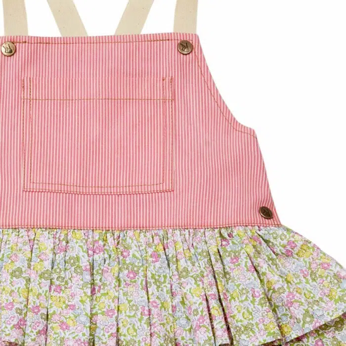Une adorable Robe Salopette Printemps été pour Fille avec Plastron avant en Coton Rose et jupe à volants fleuris liberty rose et vert. Bretelles croisées dans le dos. Ouverture avec boutons pressions dans sur les côtés. Modèle de la marque de mode pour enfants LA FAUTE A VOLTAIRE.