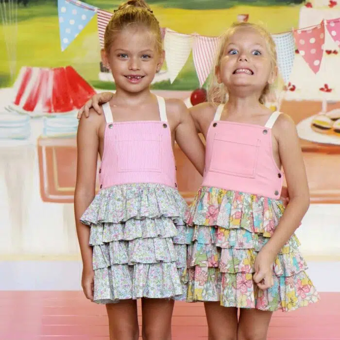 Une adorable Robe Salopette Printemps été pour Fille avec Plastron avant en Coton Rose et jupe à volants fleuris liberty rose et vert. Bretelles croisées dans le dos. Ouverture avec boutons pressions dans sur les côtés. Modèle de la marque de mode pour enfants LA FAUTE A VOLTAIRE.