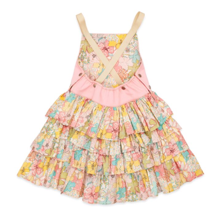 Une adorable Robe Salopette Printemps été pour Fille avec Plastron avant en Coton Rose et jupe à volants fleuris liberty dans les tons abricot, jaune, vert. Bretelles croisées dans le dos. Ouverture avec boutons pressions dans sur les côtés. Modèle de la marque de mode pour enfants LA FAUTE A VOLTAIRE.