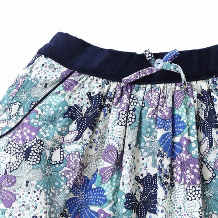 Somptueux ensemble d'hiver pour toutes les filles et fillettes fan de mode ! Un sous pull col roulé beige à manches longues assorti à une jupe fleurie liberty bleue et lilas de la marque de mode pour enfants LA FAUTE A VOLTAIRE.