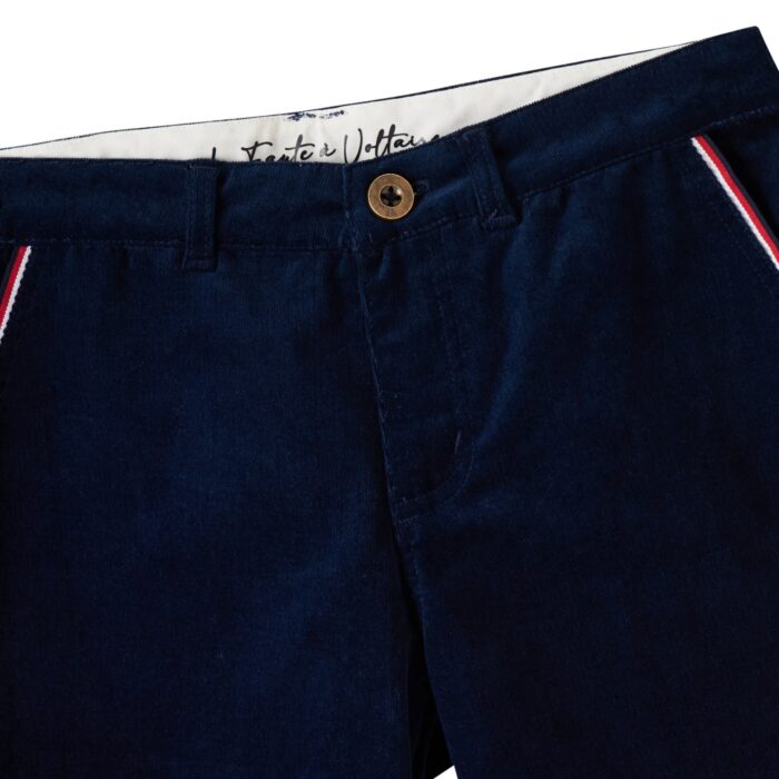 Un Élégant Pantalon Coupe Chino en Velours de Coton Bleu marine pour Garçons de 2 à 16 Ans de la Marque de Mode Française Chic pour Enfant La Faute à Voltaire. Vous aimerez le Confort de la Coupe Chino Ample aux Cuisses et Resserré aux Chevilles. Poches Raglans avec Biais Bleu Blanc Rouge. Évolutif avec son Élastique Intérieur qui permet d'Adapter la Largeur de la Taille. Écriture Décorative La Faute à Voltaire et Ruban Bleu Blanc Rouge à l'intérieur de la ceinture ainsi que de chaque côté de l'intérieur du bas du pantalon pour pouvoir le rouler vers l'extérieur si le pantalon est trop Long avec une petite Fantaisie.