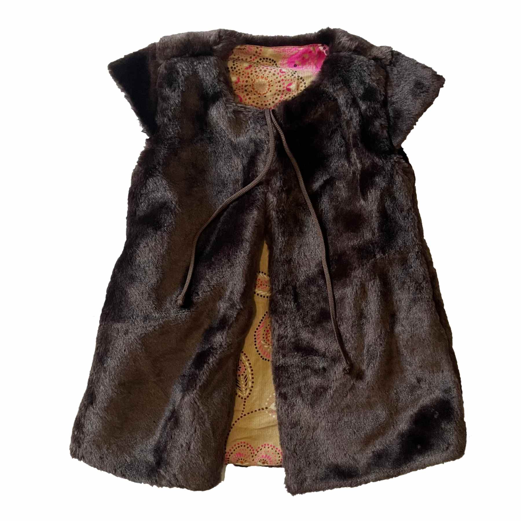 Découvrez ce gilet réversible en fausse fourrure marron toute douce, sans manches et pour filles entre 2 à 12 ans. Ce gilet est parfait pour toutes les occasions hivernales, dès le début de la rentrée scolaire, jusqu'à l'hiver. Doté d'une fausse fourrure toute douce, ce gilet apporte un confort optimal et une élégance sans égard, d'autant plus que ce gilet est réversible, offrant encore plus de possibilités de style. Offrez cet adorable gilet de la marque française de mode pour enfant en commerce équitable signé LA FAUTE A VOLTAIRE.