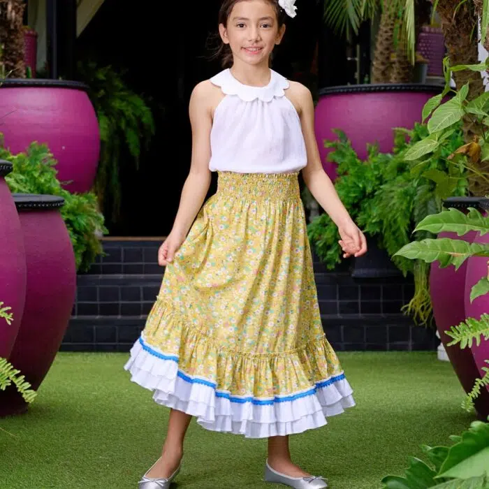 Élégante Jupe Bohème Longue Fleurie Liberty Jaune, Volants Blancs et Pompons Bleu Roi qui se Transforme en Robe Longueur Midi grâce à son Col Smocks Élastique. Jupe 2-en-1 oour Fille, Fillette et Ado de 5 à 16 ans