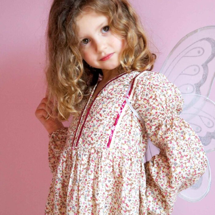 Pour la rentrée scolaire comme pour tous les jours, on craque pour cette magnifique robe imprimée fleuri liberty rose et beige à paillettes rose fuchsia. La robe à manches longues bouffantes est inspirée des robes du moyen âge avec plastron bordé de strass rose et lien sur le côté pour resserrer la robe sur les côtés. Modèle exclusif de la marque de mode Française chic pour enfant produite en commerce équitable et quantité raisonnée c'est la faute à Voltaire/ La Faute à Voltaire.