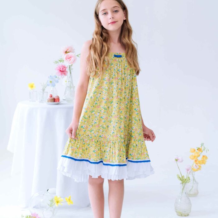 Magnifique Robe Été Coupe Large Longueur Midi en coton Fleuri Liberty Jaune, Volants Blancs et Pompons Bleu roi en Bas de la Jupe. Col Smocks Extensible. Robe Évolutive Deux-en-Un se porte façon Robe Midi ou façon Jupe Bohème Longue à Volants avec un petit Haut Blanc Assorti. Création Mode Printemps Été pour Filles, Fillettes et Ados de la Marque de Mode Française Chic pour Enfant La Faute à Voltaire.
