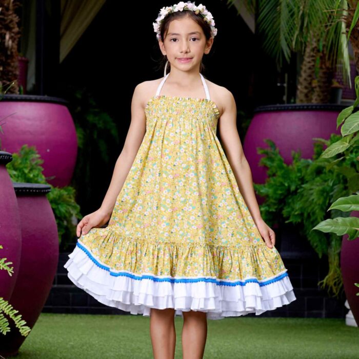 Magnifique Robe Été Coupe Large Longueur Midi en coton Fleuri Liberty Jaune, Volants Blancs et Pompons Bleu roi en Bas de la Jupe. Col Smocks Extensible. Robe Évolutive Deux-en-Un se porte façon Robe Midi ou façon Jupe Bohème Longue à Volants avec un petit Haut Blanc Assorti. Création Mode Printemps Été pour Filles, Fillettes et Ados de la Marque de Mode Française Chic pour Enfant La Faute à Voltaire.