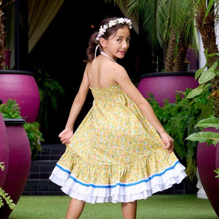 Magnifique Robe Été Coupe Large Longueur Midi en coton Fleuri Liberty Jaune, Volants Blancs et Pompons Bleu roi en Bas de la Jupe. Col Smocks Extensible. Robe Évolutive Deux-en-Un se porte façon Robe Midi ou façon Jupe Bohème Longue à Volants avec un petit Haut Blanc Assorti. Création Mode Printemps Été pour Filles, Fillettes et Ados de la Marque de Mode Française Chic pour Enfant La Faute à Voltaire.